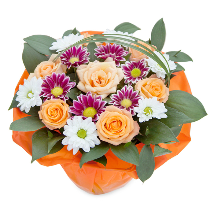 Handcrafted by local florists in Harold Wood, this lush, exuberant bouquet embodies the bright energy and welcoming spirit of the area. Against a clean, uncluttered white background, the viewer's eye is drawn to the radiant cluster of roses at the center-each blossom unfolding in tones that range from creamy peach to deep, joyful orange, resembling the warmth of late afternoon sunshine filtering through Harold Wood Park's leafy avenues. Cherished chrysanthemums intermingle as elegant fillers, their crisp white petals and vivid green centers forming daisy-like smiles, while nearby, magenta and purple varieties burst forth in star-shaped blooms with striking lime-green and yellow hearts. The arrangement's base overflows with dense, dark green foliage-perhaps ruscus or similar leafy greens-evoking the undulating textures of local gardens. A slender, arching strand of bright green grass lends a dash of contemporary grace, quietly mirroring the gentle sways of Harold Wood's open spaces. The bouquet's base is wrapped in bold crinkled orange cellophane, catching the light and enhancing every warm shade above it-a festive touch that transforms the arrangement into a poetic celebration, ready for gifting. Every element is placed with meticulous skill, reflecting not just an artistic eye but a deep-rooted knowledge of the area's traditions and love of seasonal beauty. This bouquet feels alive with possibility, perfect for marking special moments, anniversaries, or simply to sprinkle a little Harold Wood happiness into everyday life.